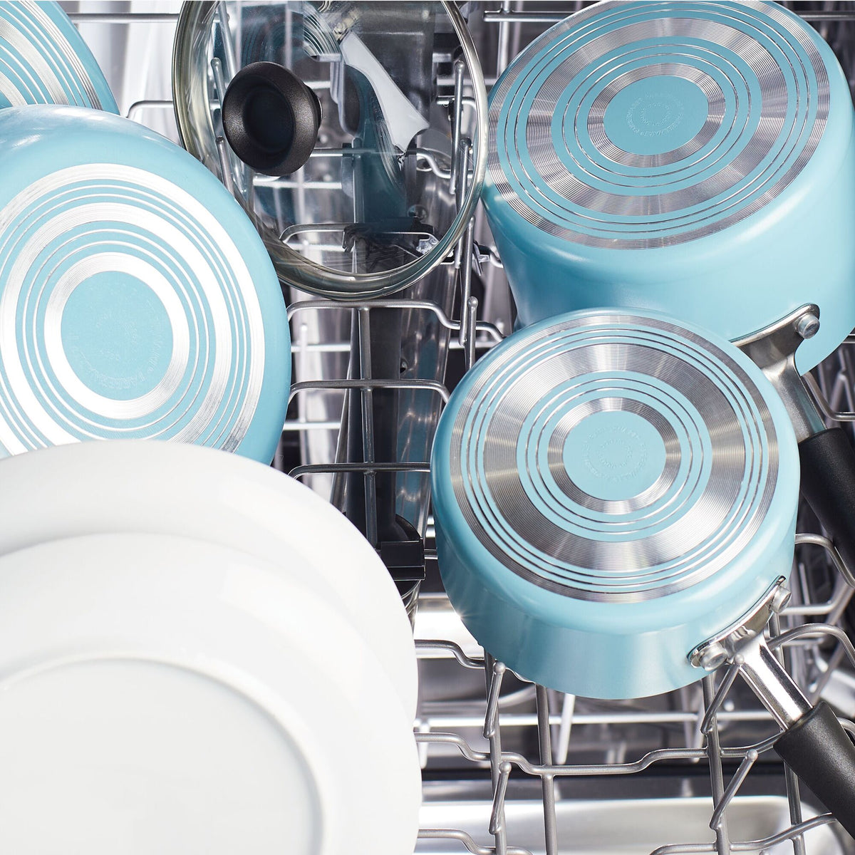 Blue pots and white dishes arranged in a dishwasher rack.