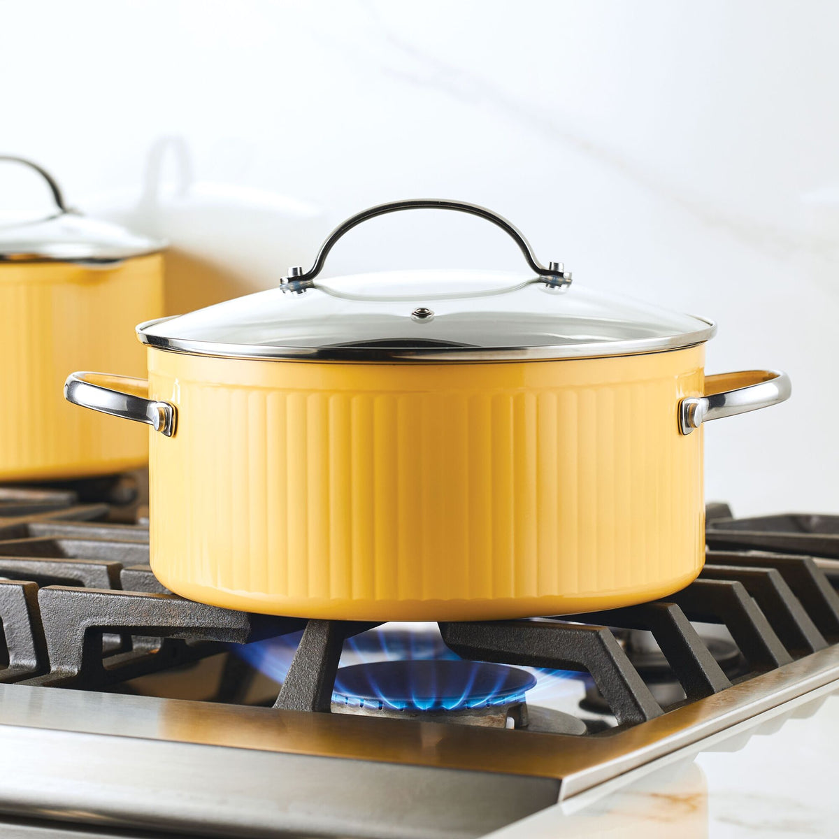 Yellow pot on a lit gas stove burner in a kitchen setting.