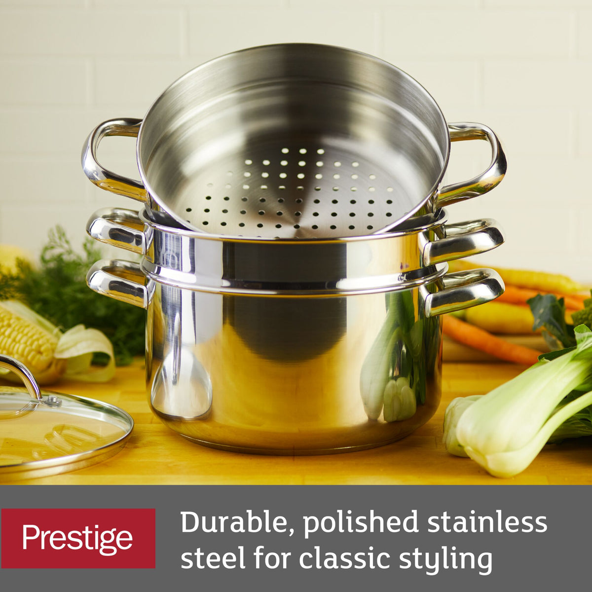 Polished stainless steel steamer and pot set with vegetables in background.