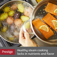 Salmon and lemon slices steaming above boiling potatoes in a kitchen.
