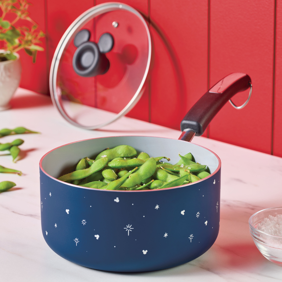 Blue saucepan with edamame, lid nearby, on a marble countertop.