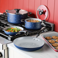 Cookware set with blue pots and pans on a stove; cookies on a baking sheet.