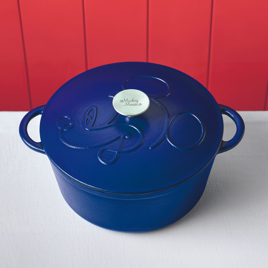 Blue cast iron pot with Mickey Mouse design on red background.