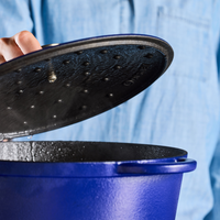 Person lifting lid of a blue pot.
