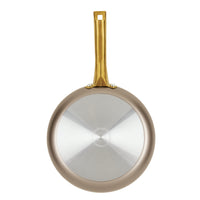 A frying pan from the Radiant Nonstick 12-Piece Cookware Set, featuring a silver bottom and a gold accent handle, viewed from above to highlight its elegant design and nonstick surface for even heat distribution.