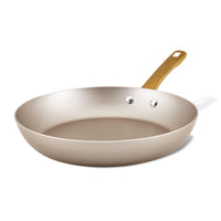 The Radiant Nonstick Frying Pan, showcasing a champagne-colored surface and a golden handle, is elegantly presented against a white background. Its design guarantees even heat distribution, combining functionality with style in any kitchen environment.