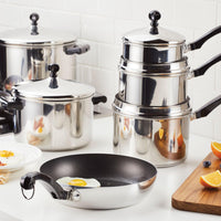 Stainless steel cookware and a frying pan with eggs in a kitchen.