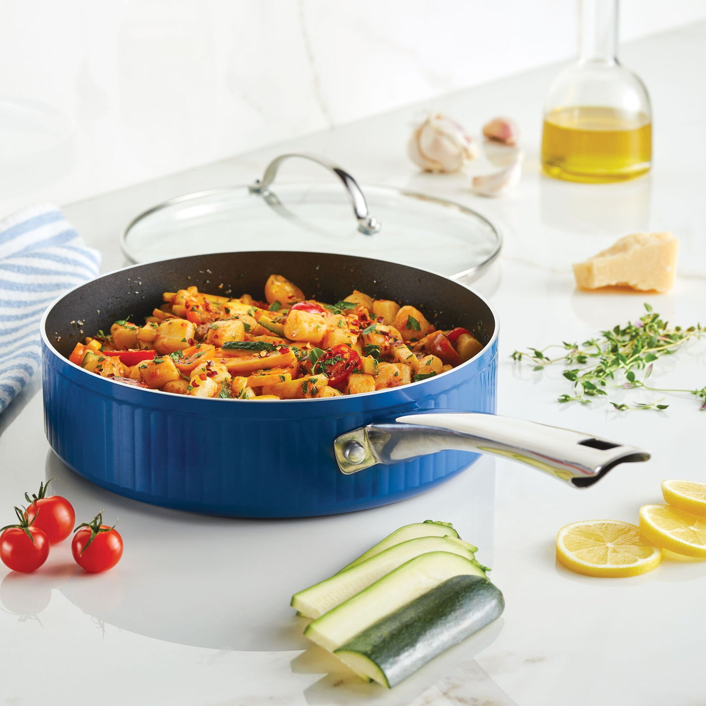A Style Nonstick Cookware Saute Pan with Lid, 3-Quart, in blue sits on the kitchen counter filled with cooked pasta and vegetables, highlighting the brilliant efficiency of DiamondMax™ Nonstick technology.