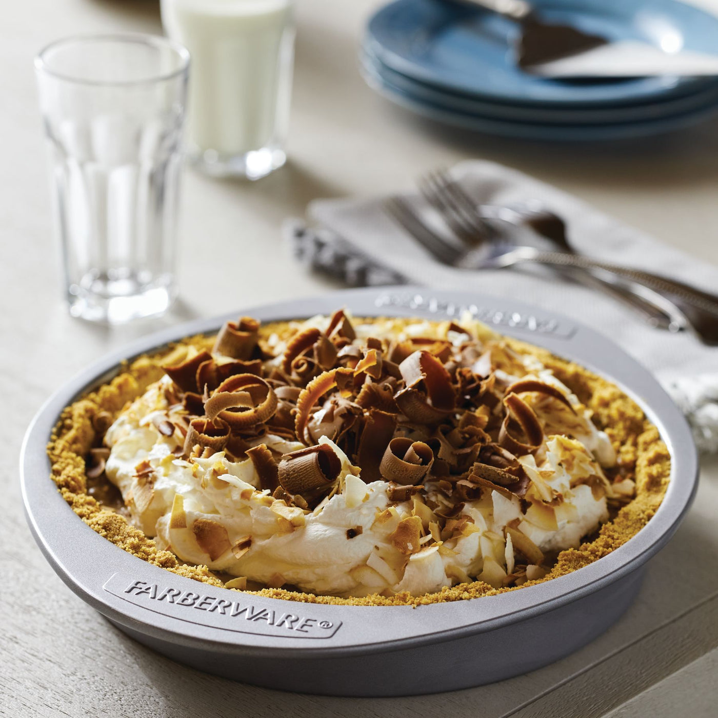A chocolate cream pie topped with whipped cream and chocolate shavings, presented in a durable 9-inch nonstick round cake pan for effortless cleanup.