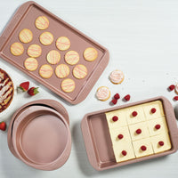 Using the 9-Inch Round Cake Pan, enjoy baked goods on trays that showcase round cakes, cookies, and raspberry-topped squares. The durable nonstick surface ensures easy cleanup.