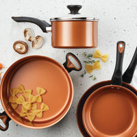 The 12-Piece Copper Ceramic Nonstick Cookware Set, equipped with advanced CopperSlide technology, is ideal for easily cooking pasta and mushrooms on a spotless white countertop.