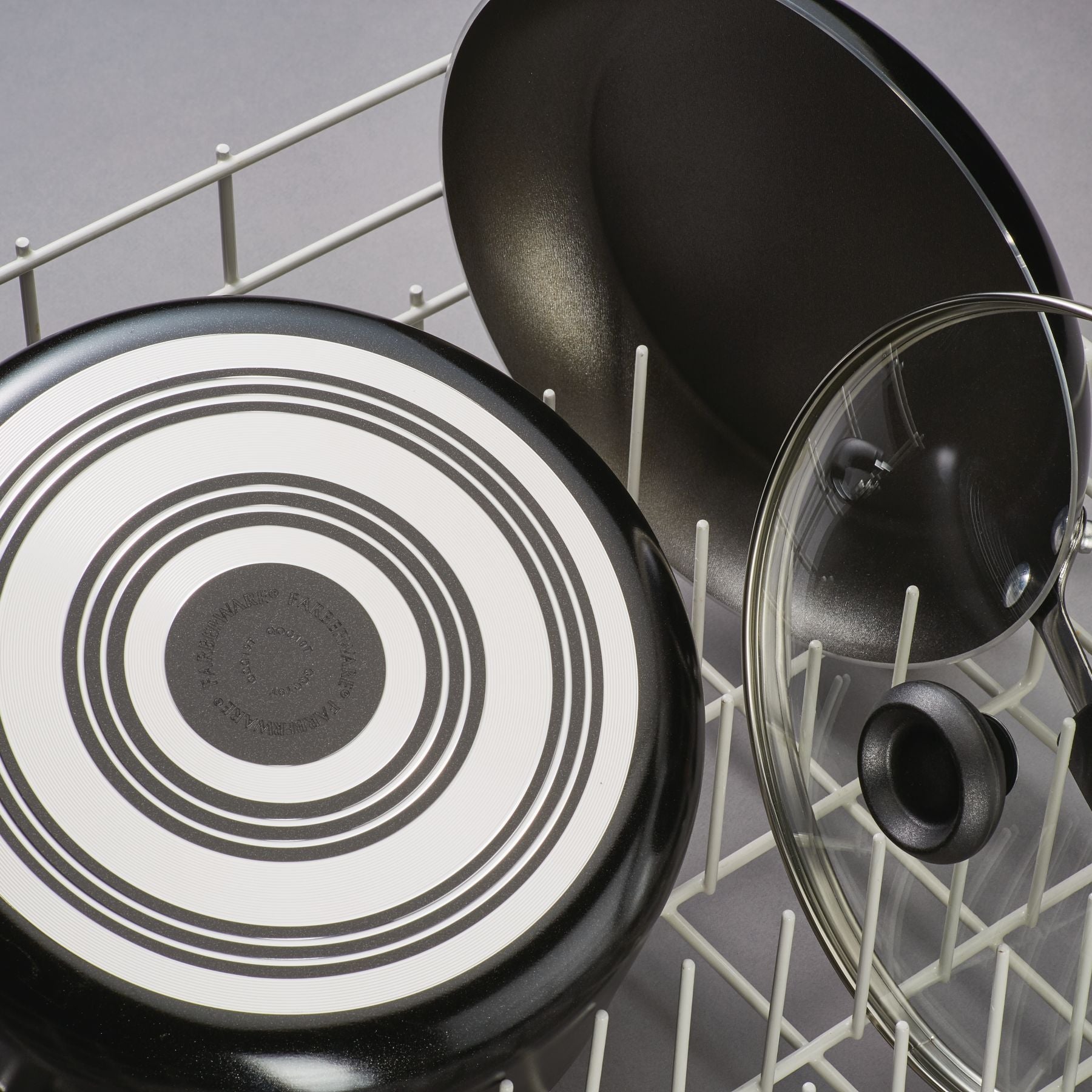 The Nonstick Frying Pan is placed in the dishwasher rack alongside its lid, highlighting its durable aluminum construction that guarantees effortless cleaning and lasting durability.