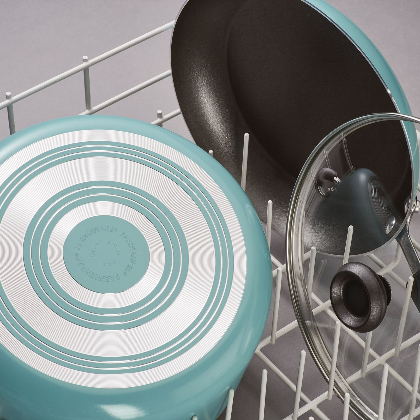 The Nonstick Frying Pan, made with durable aluminum construction, is neatly placed in the dishwasher rack alongside a pot lid.
