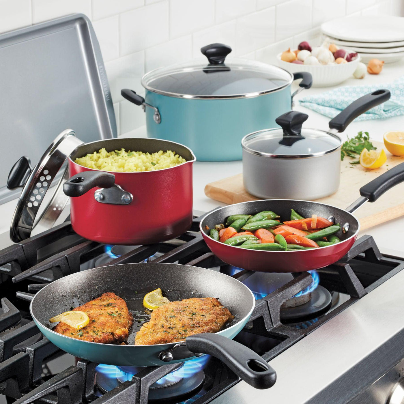 Four kitchen vessels, featuring the 10.5-Quart Nonstick Stockpot, cook a variety of foods on a stove and are ideal for family-sized servings.
