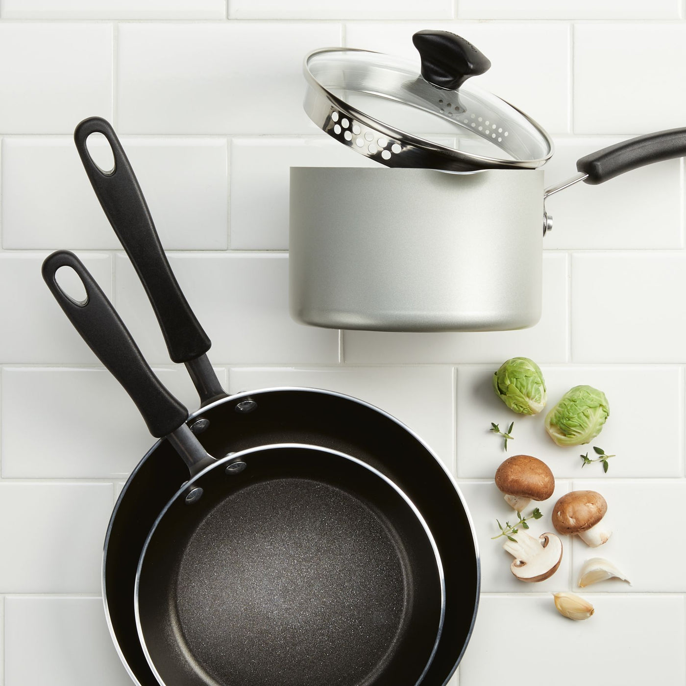 A complete 15-Piece Nonstick Cookware Set, featuring advanced DiamondMax technology, is accompanied by fresh vegetables and herbs, ensuring an effortless cooking experience with two frying pans and a pot with lid.